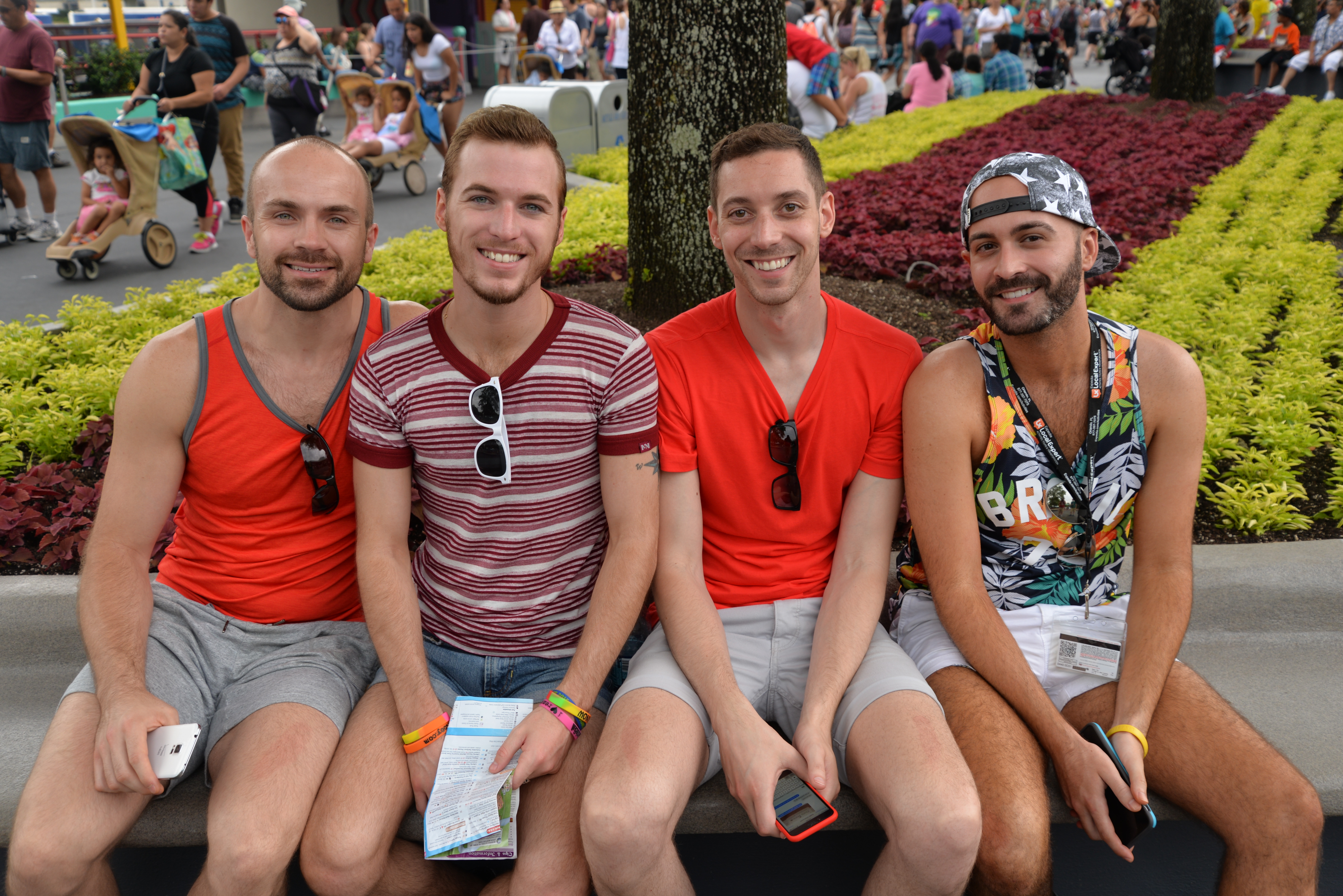 Four men sit on a bench at a GayDays event.
