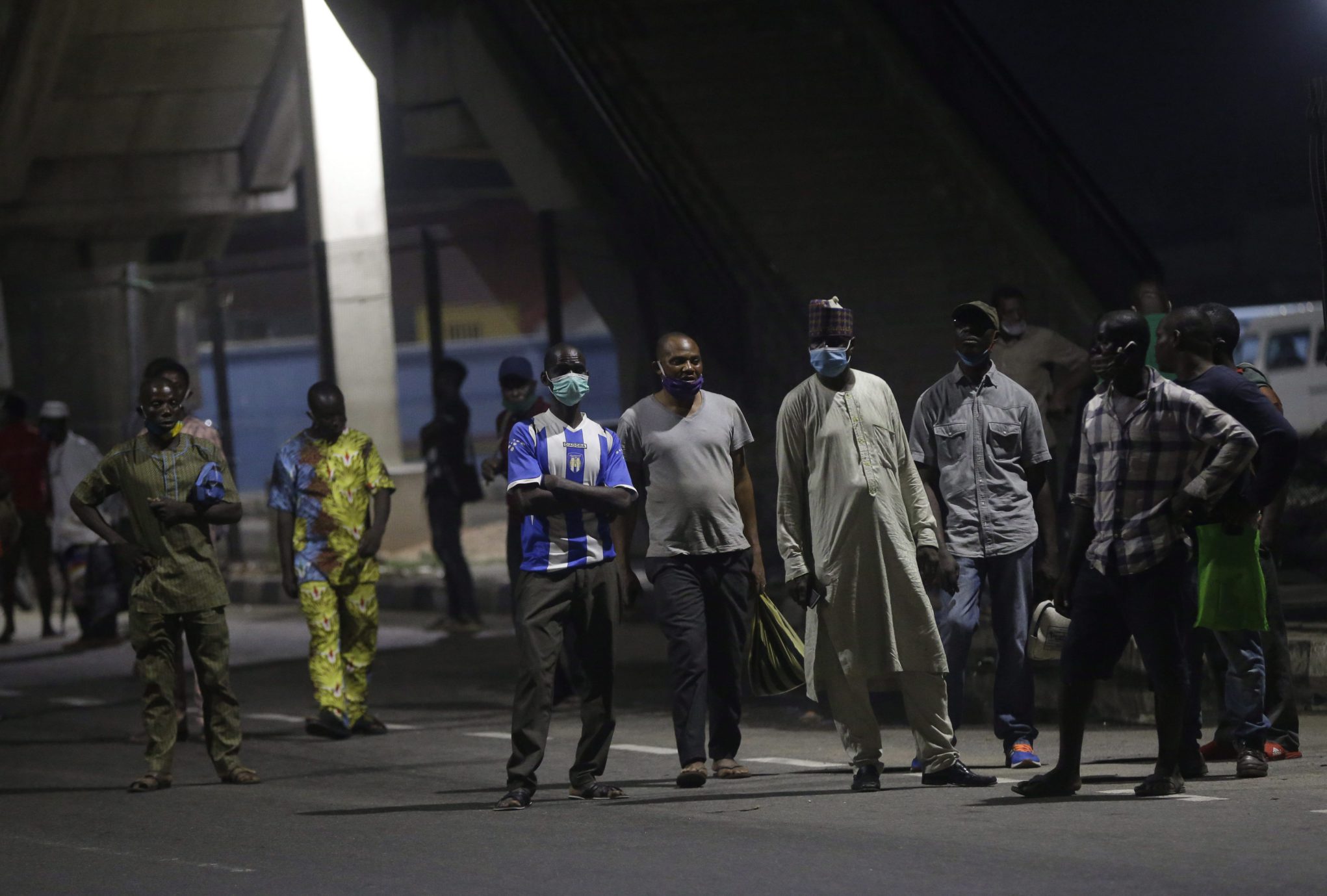 People stand at a bus stop after curfew in Lagos Nigeria.