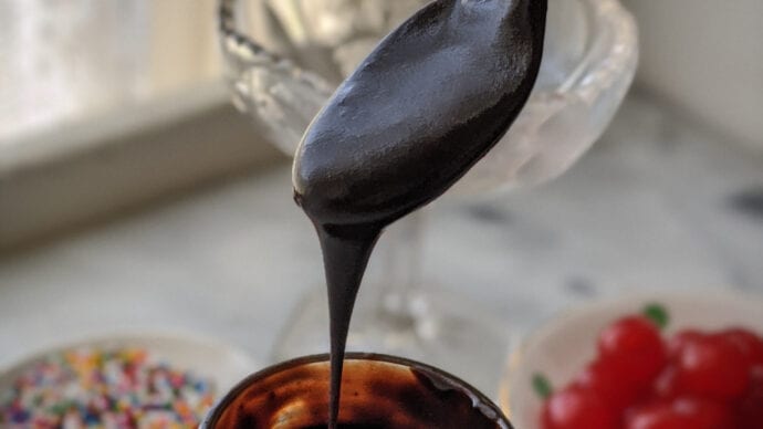 A photo of hot fudge sauce dribbling from a spoon