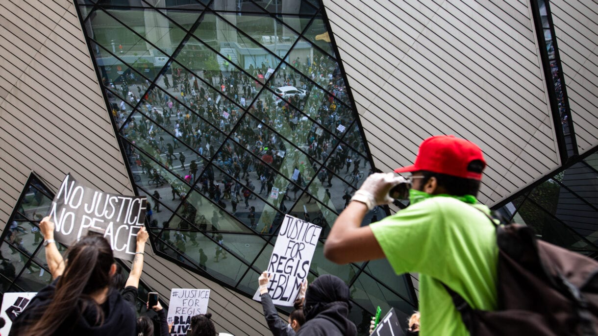 Protesters are seen reflected in the windows of the ROM.