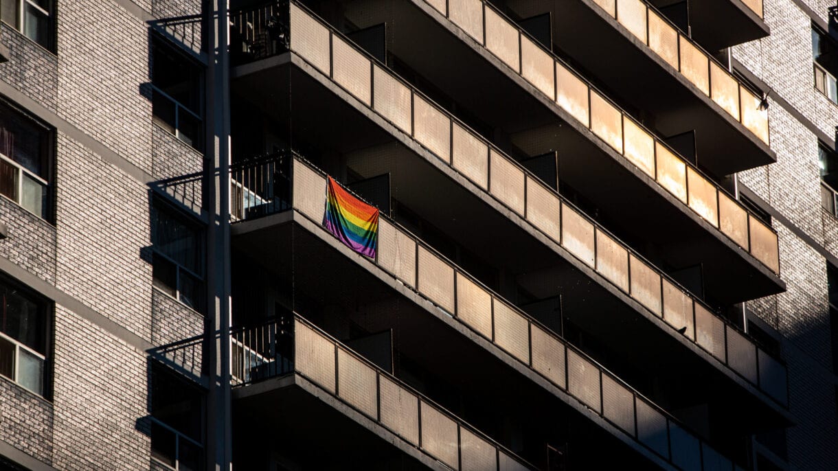 A lone Pride flag hangs off a balcony in the sunset, June 28.