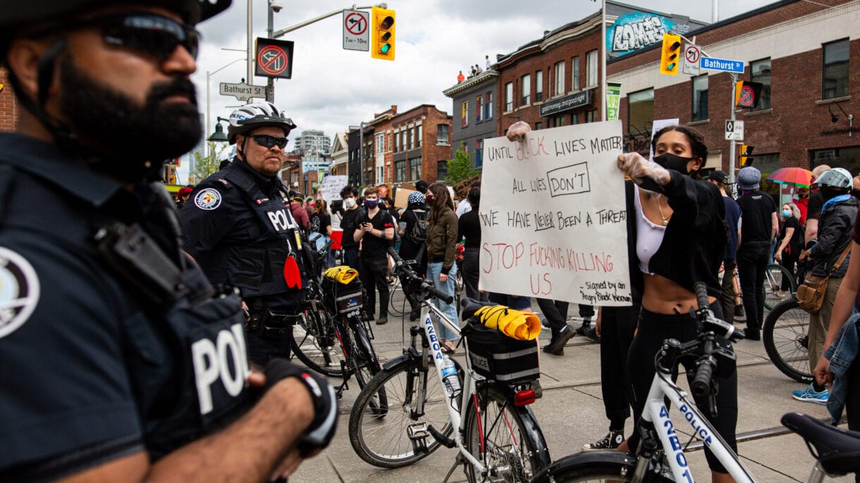 A police officer ignores a protester holding a sign stating 