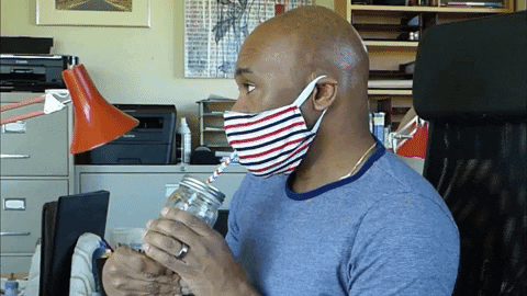 Man in a mask sips a drink from a mason jar