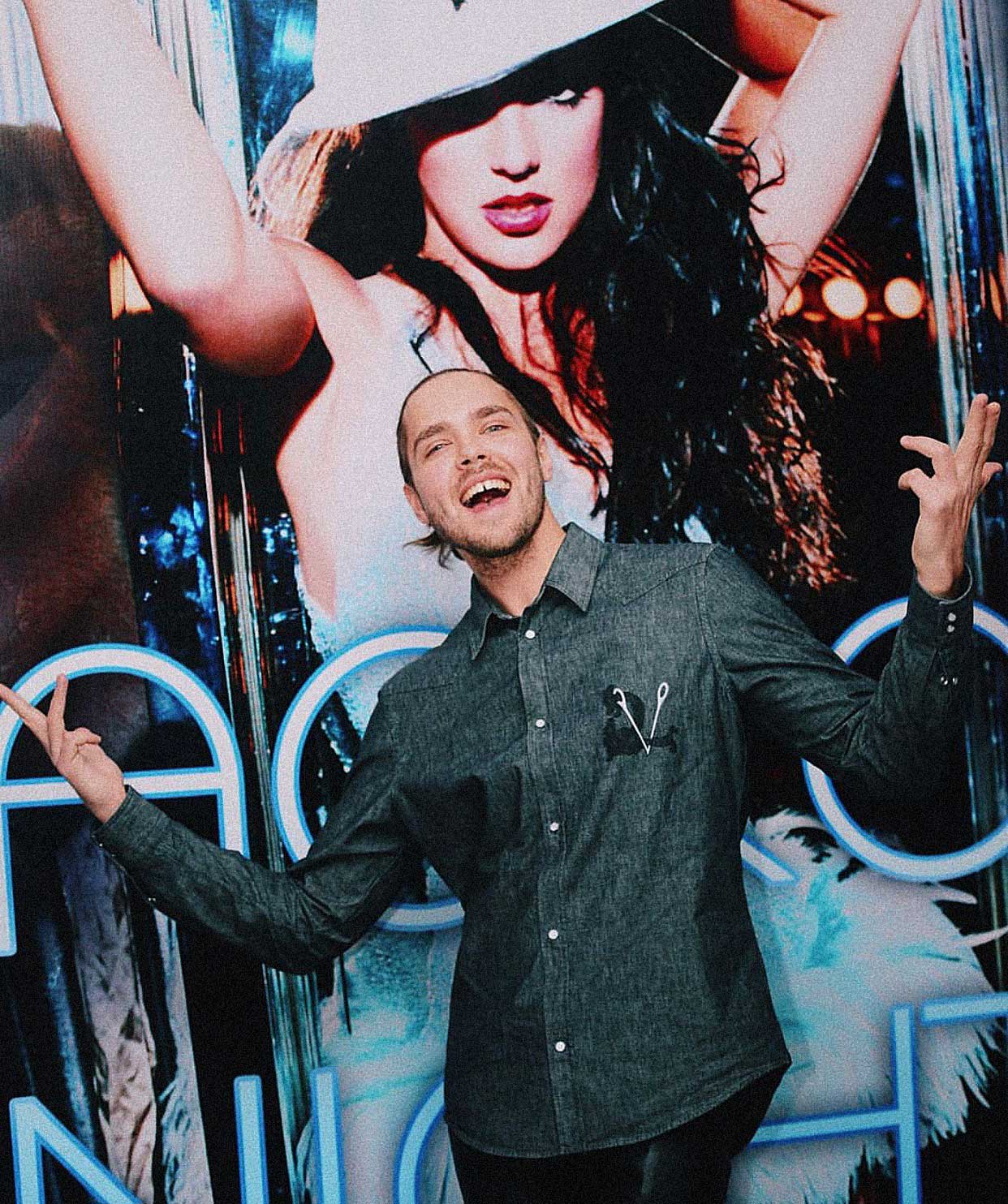 Aleksander is seen in front of a large Britney poster.