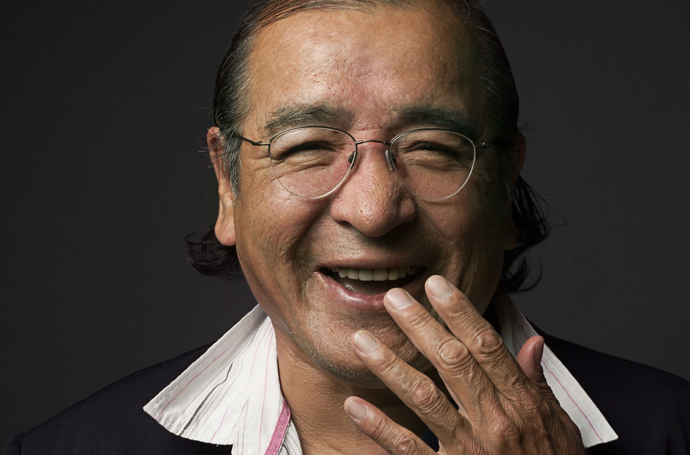 Writer Tomson Highway laughs with his hand almost cover his mouth.