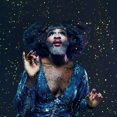 A black bearded queen in sapphire blue sequins looks up at the starry night sky.