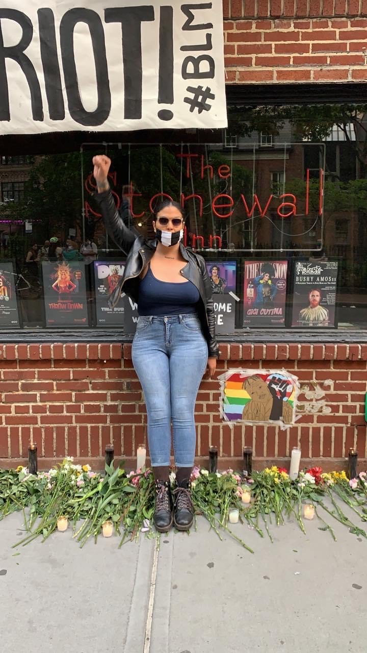 Mariah Lopez poses with her fist up in front of the Stonewall Inn