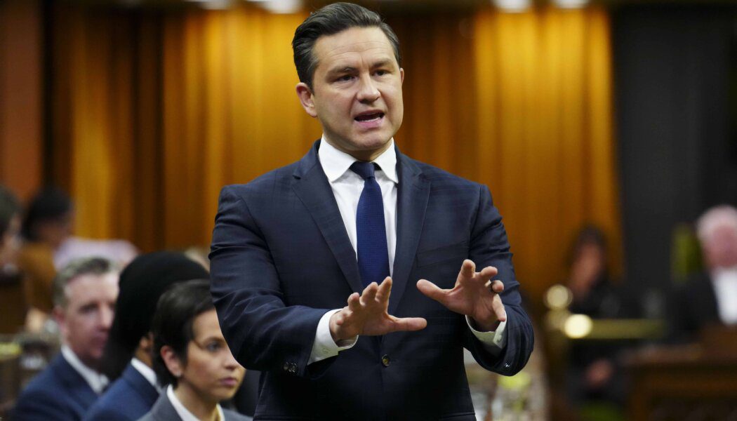 Conservative Leader Pierre Poilievre wears a suit and blue tie; he gestures with his hands while speaking.
