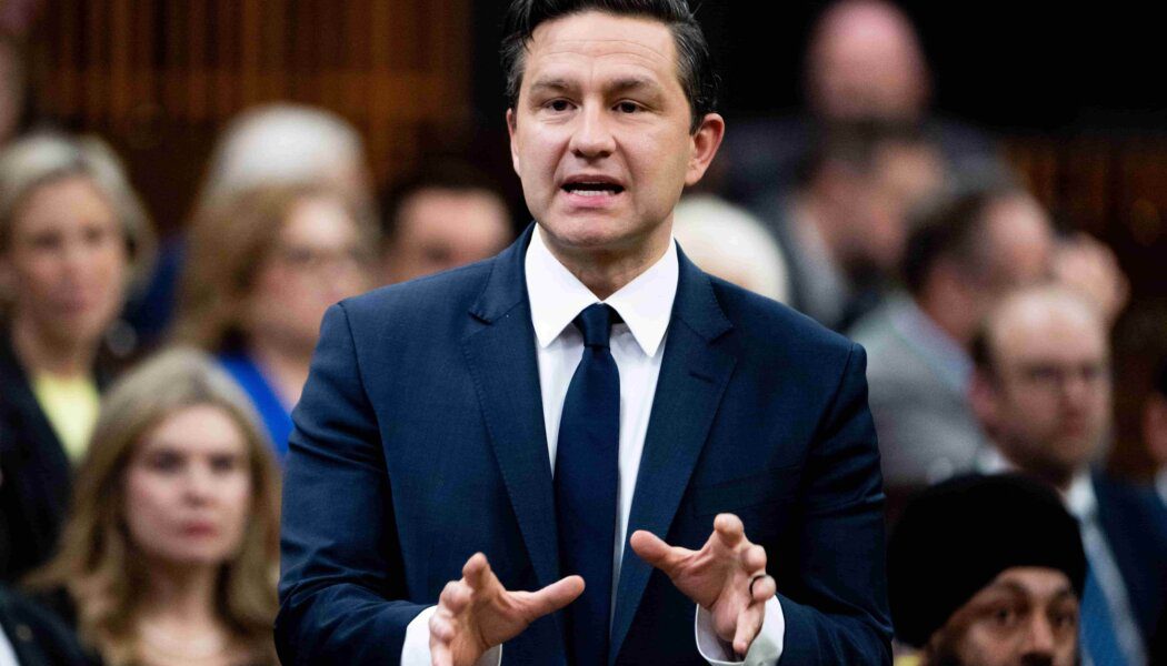 Conservative Party Leader Pierre Poilievre wears a suit and tie; he makes hand gestures while rising during Question Period. A crowd is seated behind him.