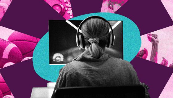 A person with a ponytail and collared shirt, from behind, looking at a computer screen and wearing over-the-ear headphones