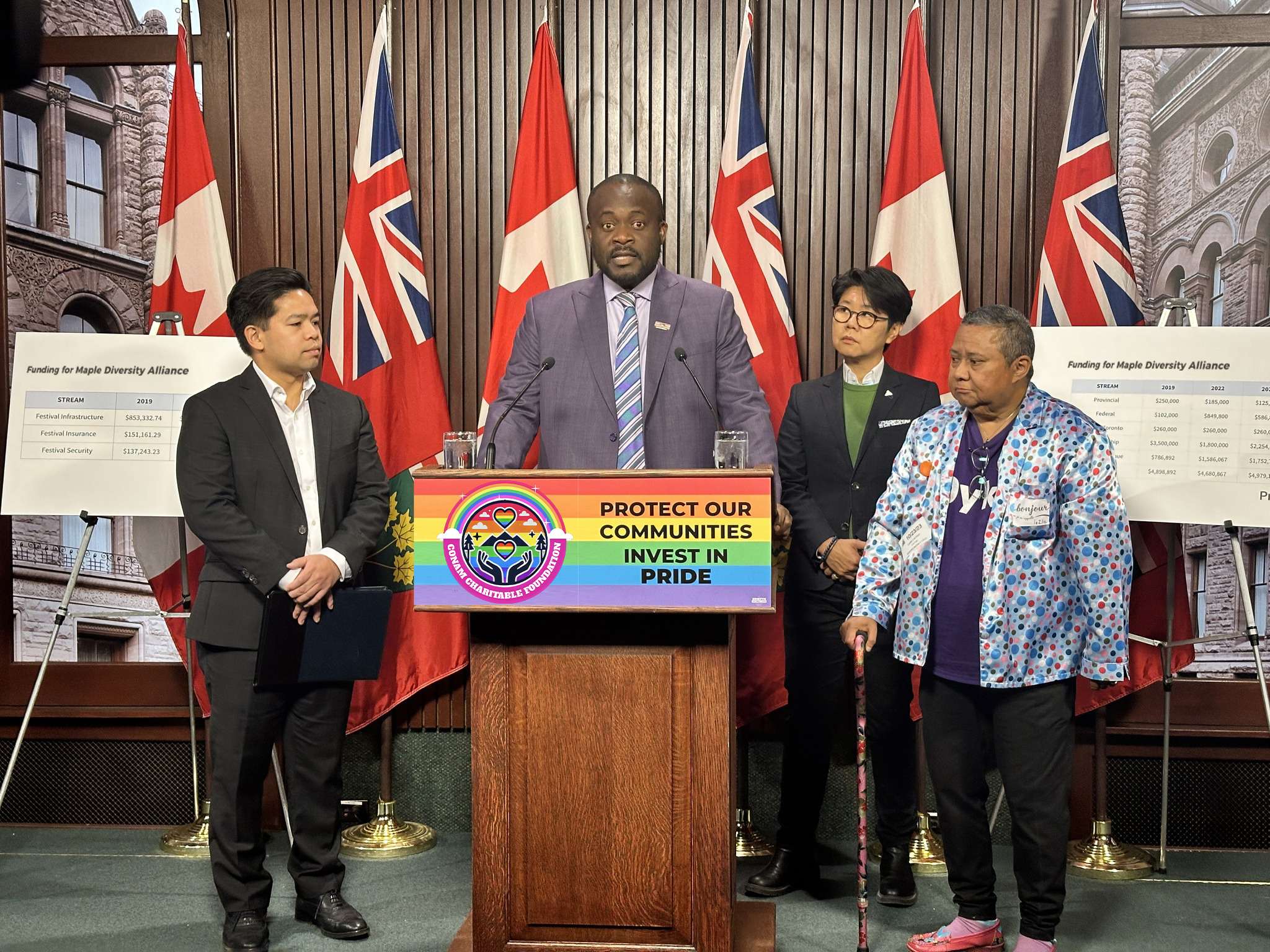 Four people beside and behind a podium with a banner that says "PROTECT OUR COMMUNITIES INVEST IN PRIDE"