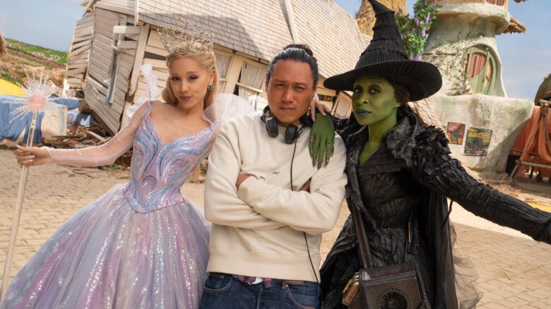 Caption L to R: Ariana Grande (as Glinda), Director Jon M. Chu, and Cynthia Erivo (as Elphaba), on the set of WICKED FOR GOOD, directed by Jon M. Chu.