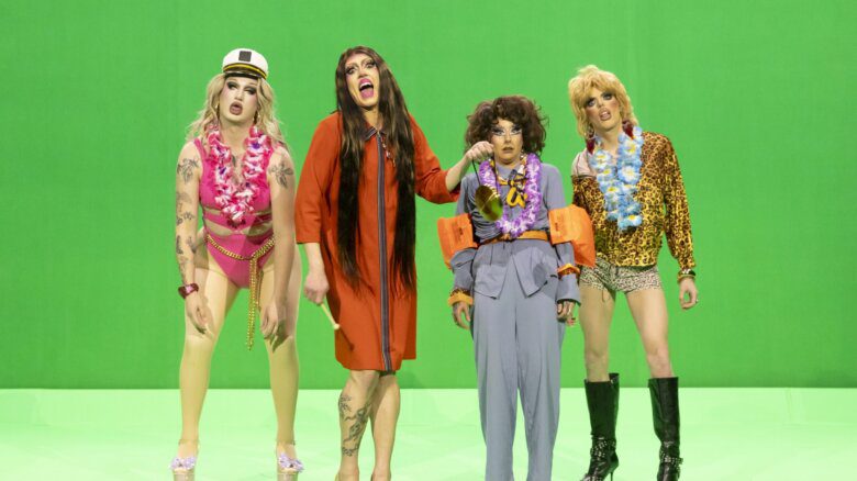Four drag performers stand in front of a green screen