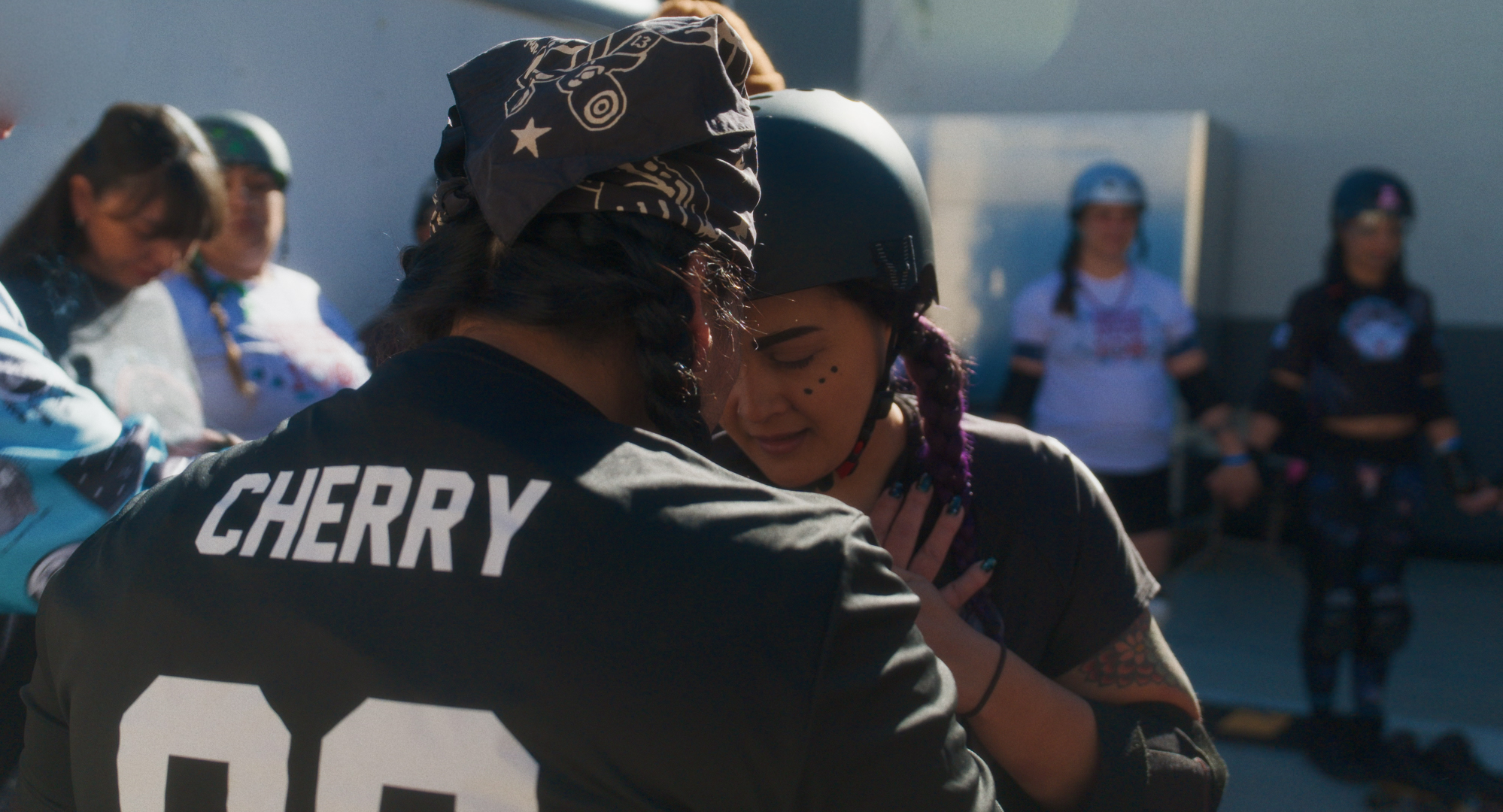 Two rollerderby players embraing with their heads bowed
