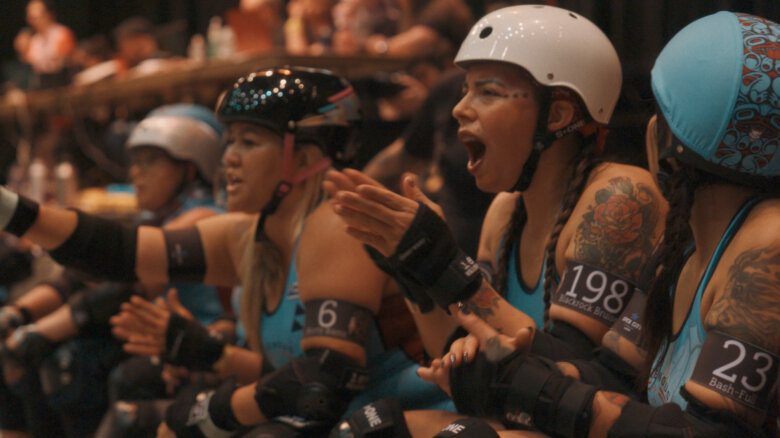 Several roller derby players cheering while seated
