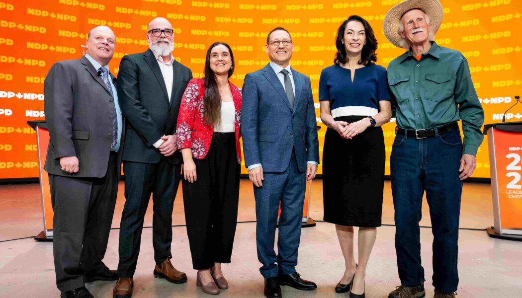 NDP leadership candidates Rob Ashton, Tanille Johnston, Avi Lewis, Heather McPherson and Tony McQuail pose for a photo. The background is orange with the NDP logo stamped on it.