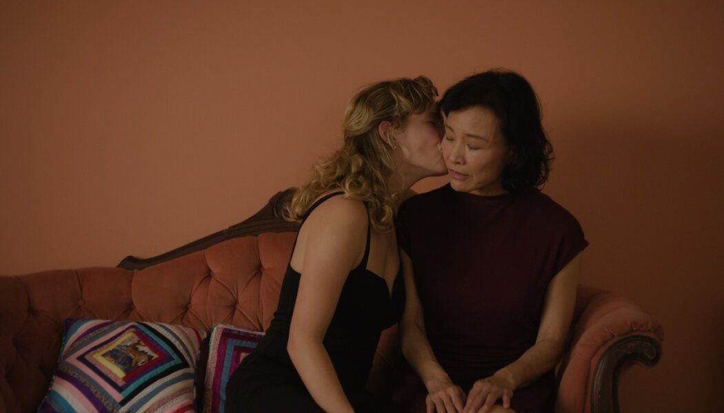Joan Chen being kissed on the cheek by a woman