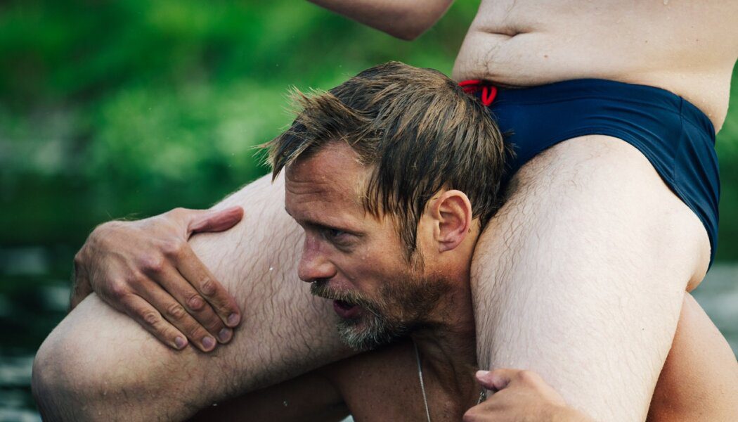 Alexander Skarsgard holding a man on his shoulders