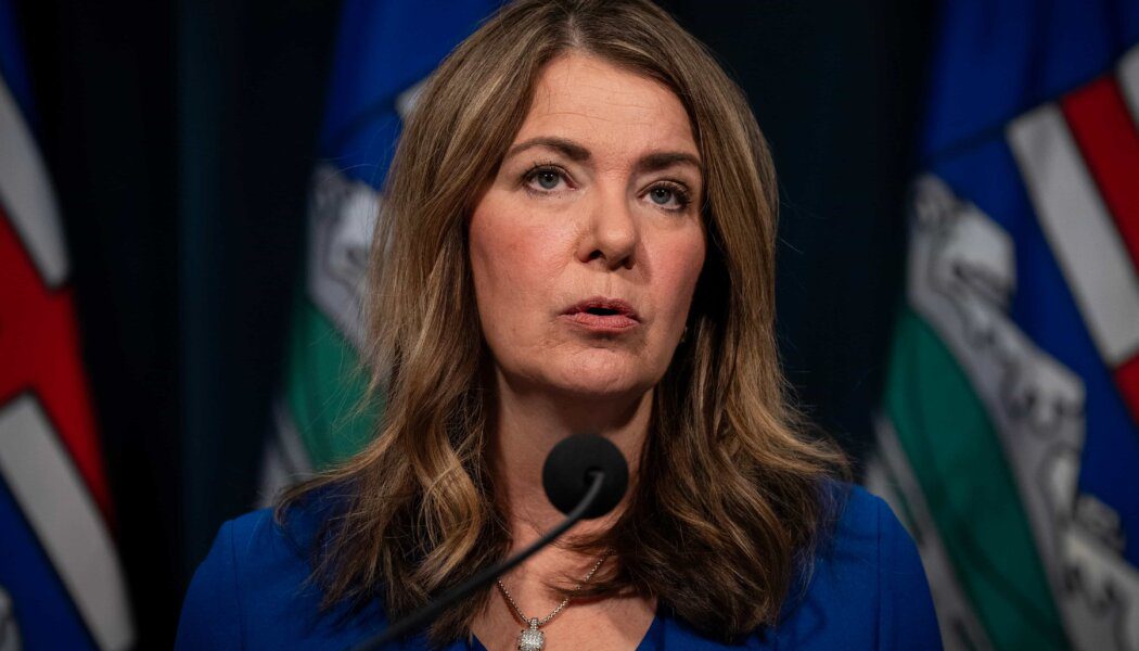 Danielle Smith standing in front of a podium wearing blue.