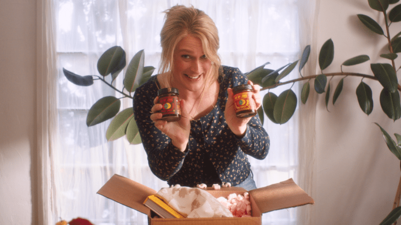 John Early in Maddie's Secret holding two jars above an open box