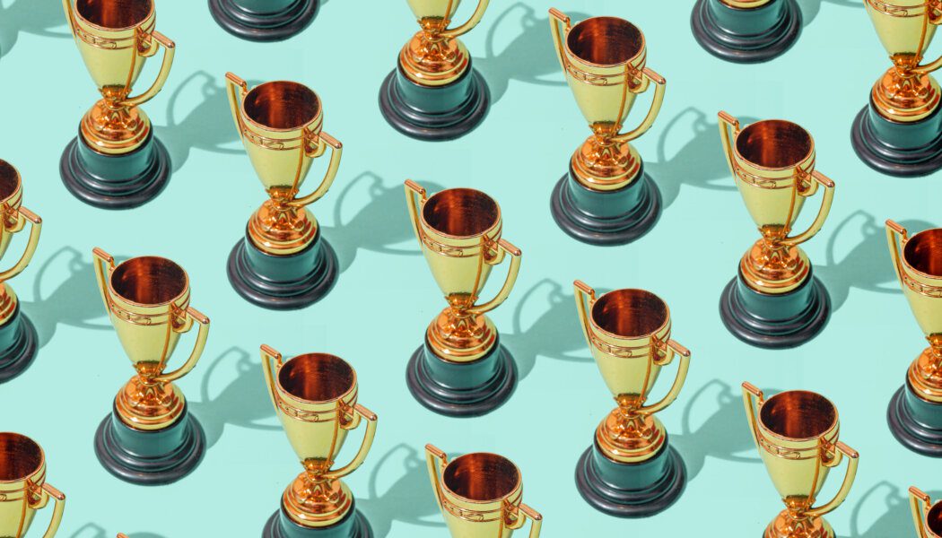High angle view of many winner gold cup trophies on blue green background. Harsh light. Concept of winner, victory, champion, world champion, sport.