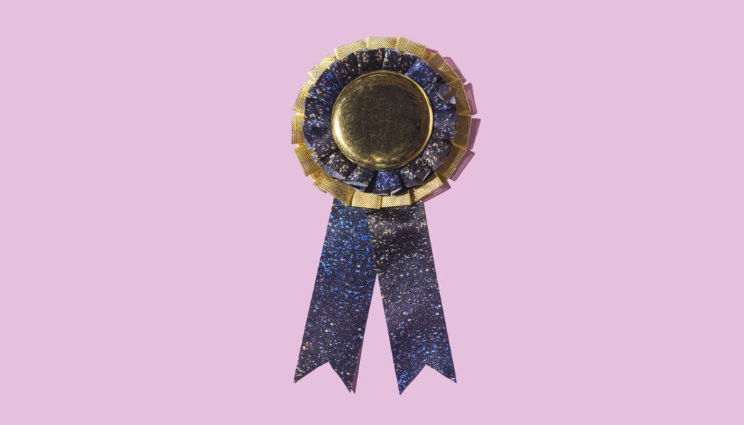 Blue award with ribbon and gold trim against a pink background