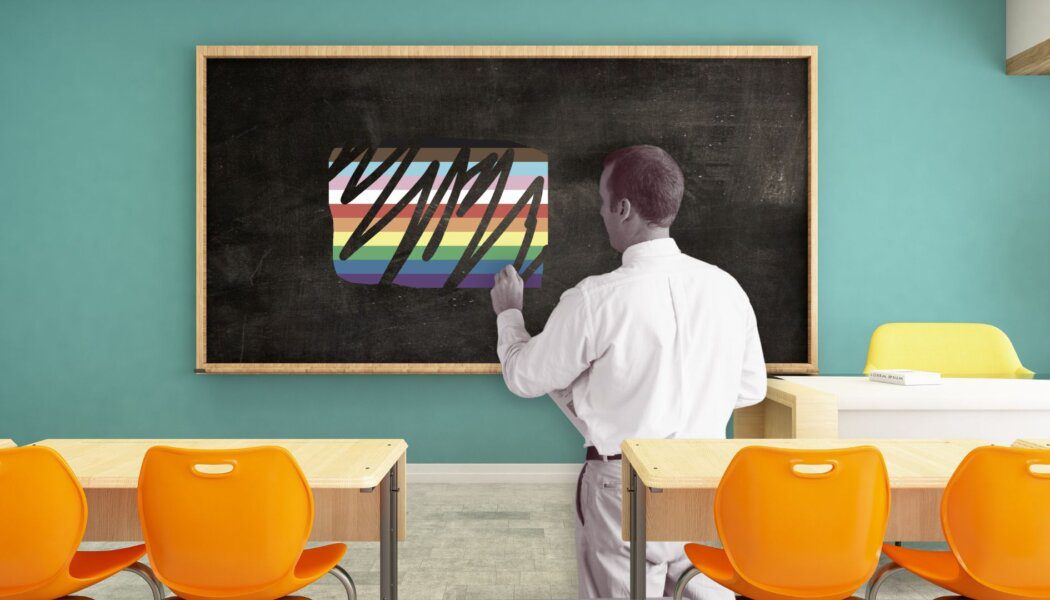 A teacher standing at a blackboard that has a Pride flag scribbled out on it