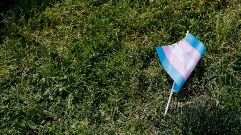 A trans flag is seen discarded on the grass